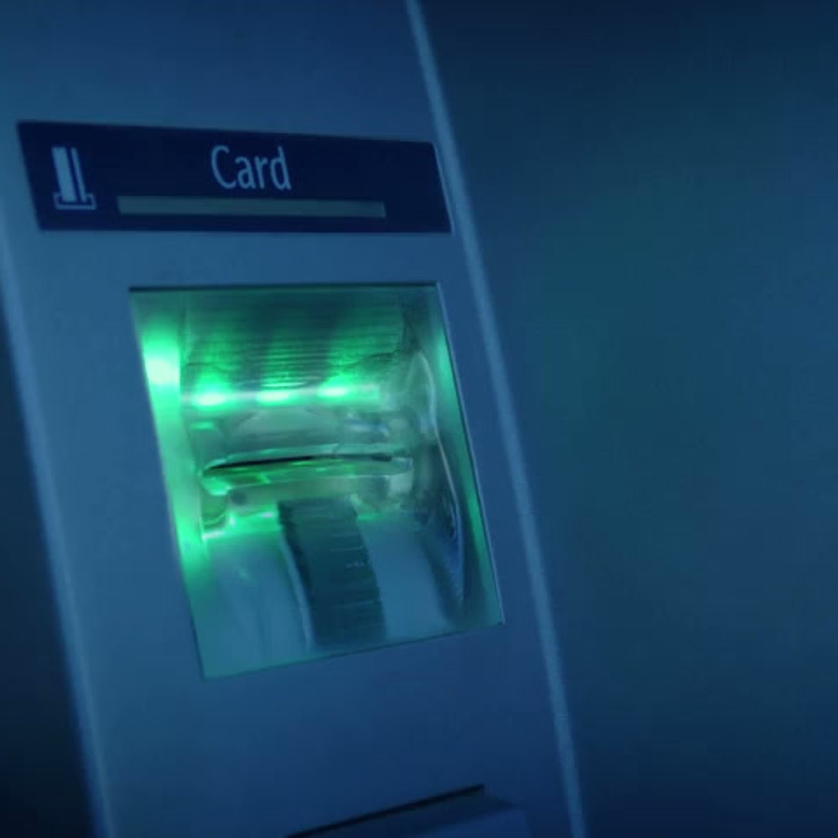 Close-up of an illuminated green ATM card reader slot.